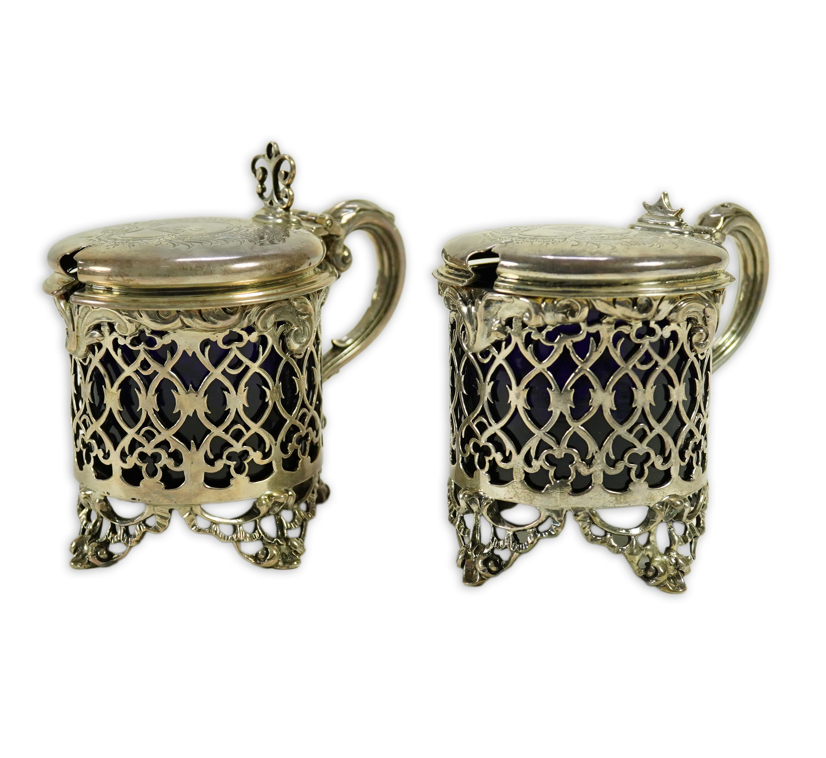 A near pair of ornate Victorian pierced silver drum shaped mustard pots and covers, one by Charles Thomas Fox & George Fox, the other by George Fox